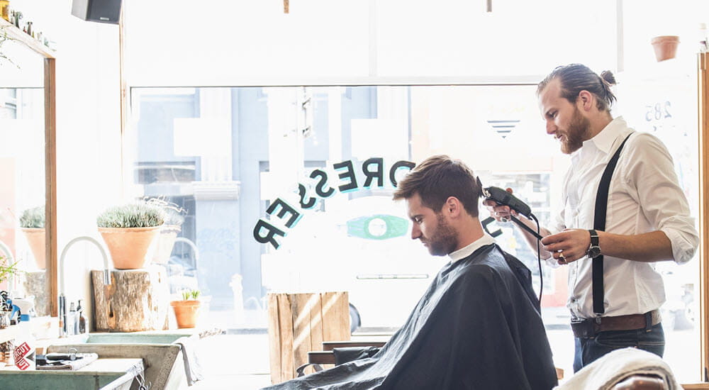 Male stylist cutting hair of customer in barber shop